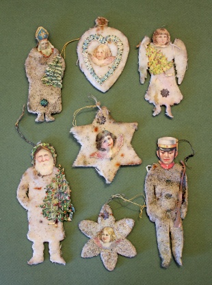 Figuren oder auch Sterne, Herzen und Blumen werden mit einem Band versehen, um sie an den Zweigen aufzuhängen. Geflügelte Engelsköpfchen, Weihnachtsmanngesichter oder ein Soldatenkopf aus Lackpapier illustrieren die Figuren.