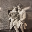 Schwarzweiß Foto: Hella Kohn sitzt auf eine Sofoa, ihre Tochter Jutta sitzt auf ihren Beinen.
